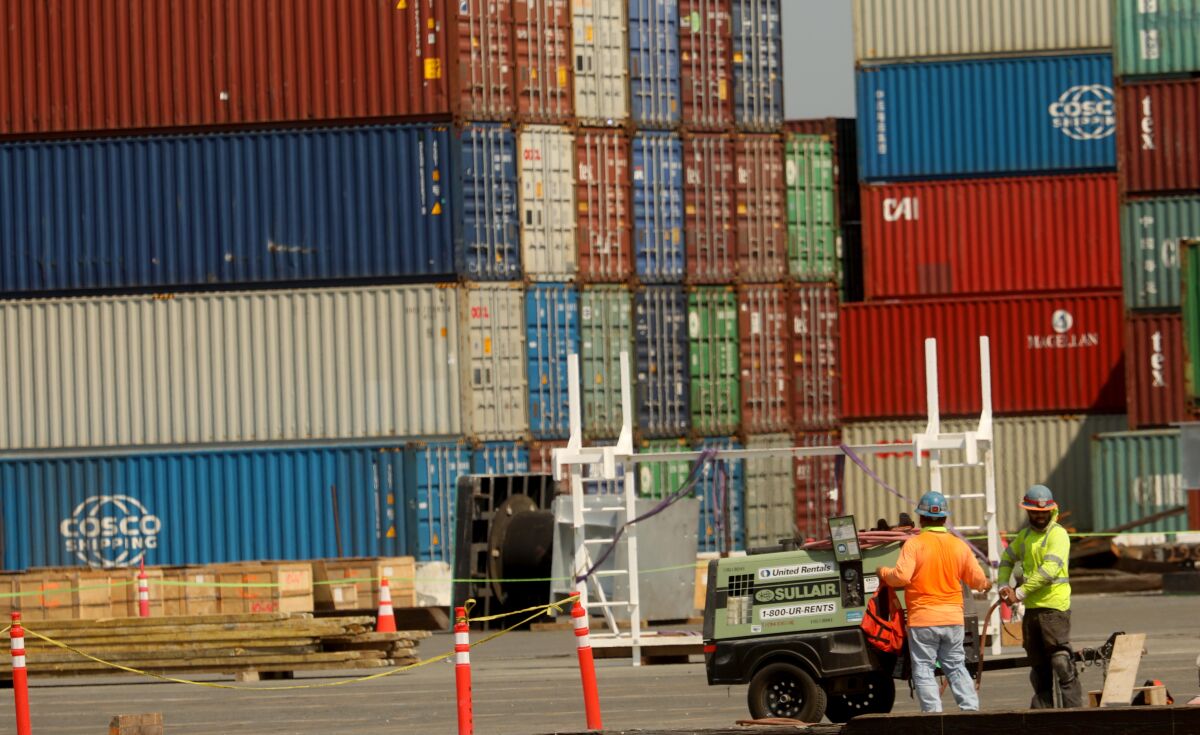 This photo shows men working with shipping containers in the background.
