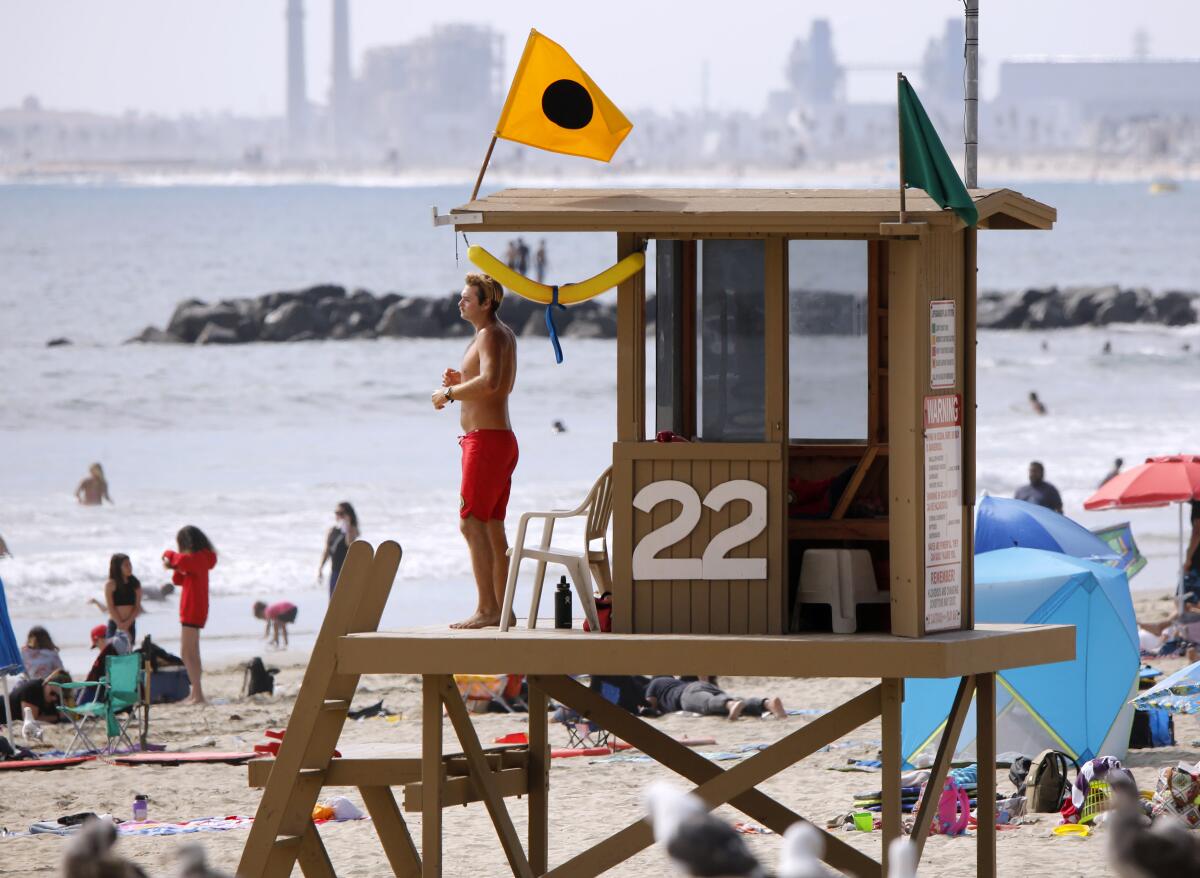 A Newport Beach lifeguard keeps an eye on beach-goers near the Newport Pier on July 1, 2020. 