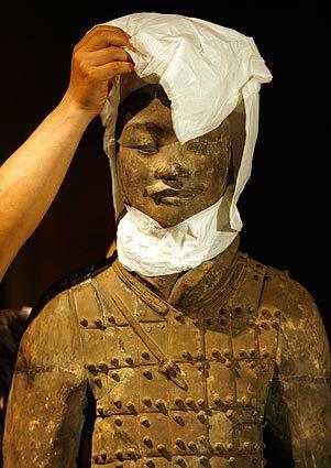 Workers unveil one of the ancient statues that arrived May 4 in the U.S. for the "Terra Cotta Warriors: Guardians of Chinas First Emperor exibition at the Bowers Museum in Santa Ana. The objects, buried for 2,000 years, had been commissioned for the tomb of Emperor Qin Shi Huang.