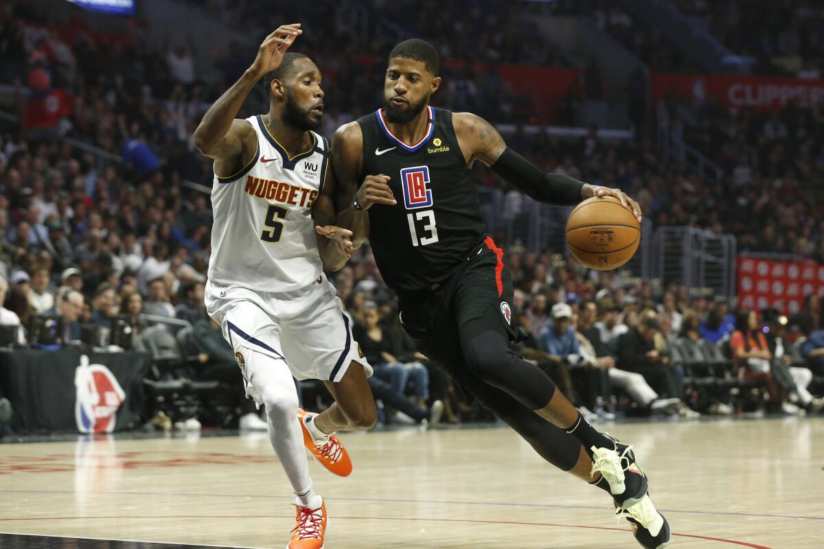Clippers guard Paul George drives to the basket guarded by Denver Nuggets forward Will Barton.