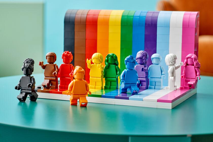 Various rainbow-colored Lego figurines displayed on a blue table