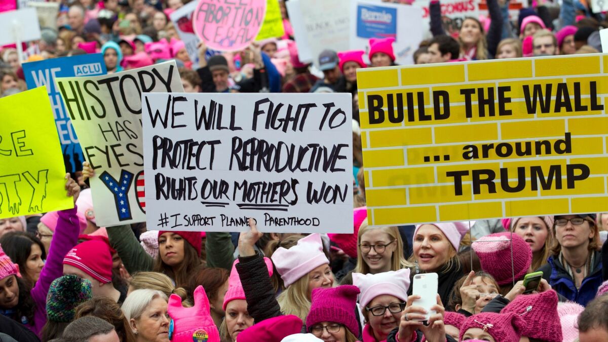 Protesters with bright pink hats and signs begin to gather early on Jan. 21, the first full day of Donald Trump's presidency, in Washington, D.C.