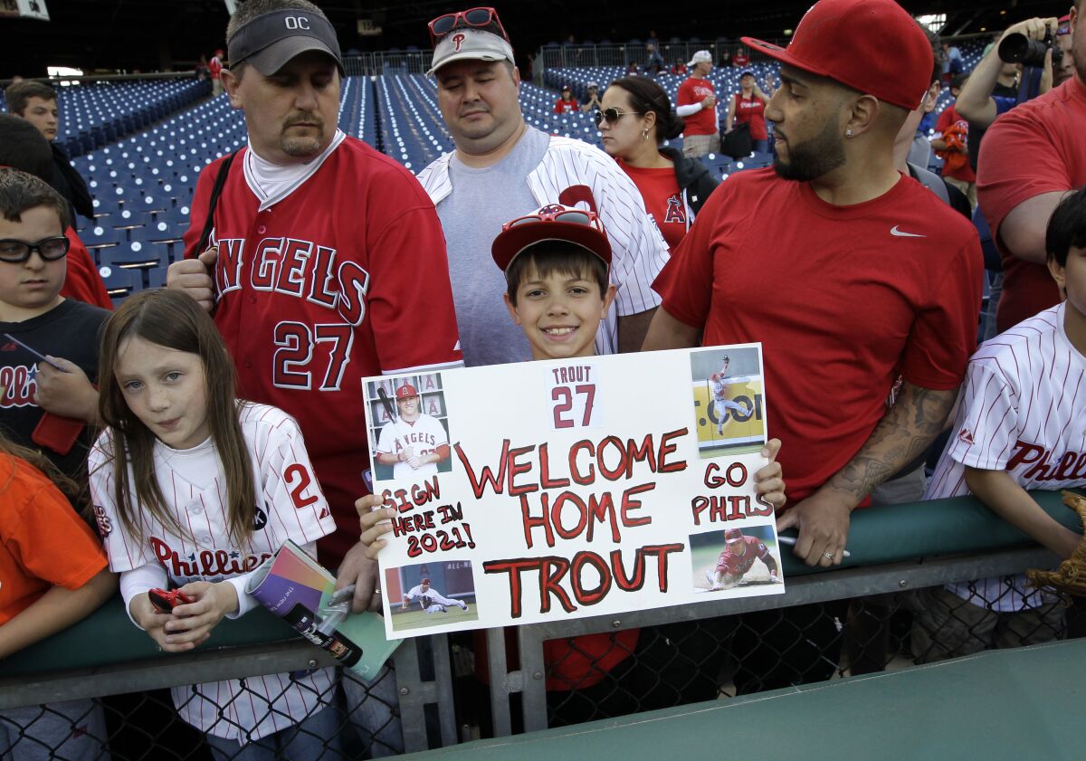 Justin Shephard holds up a sign for Angels' Mike Trout before the start of a game.