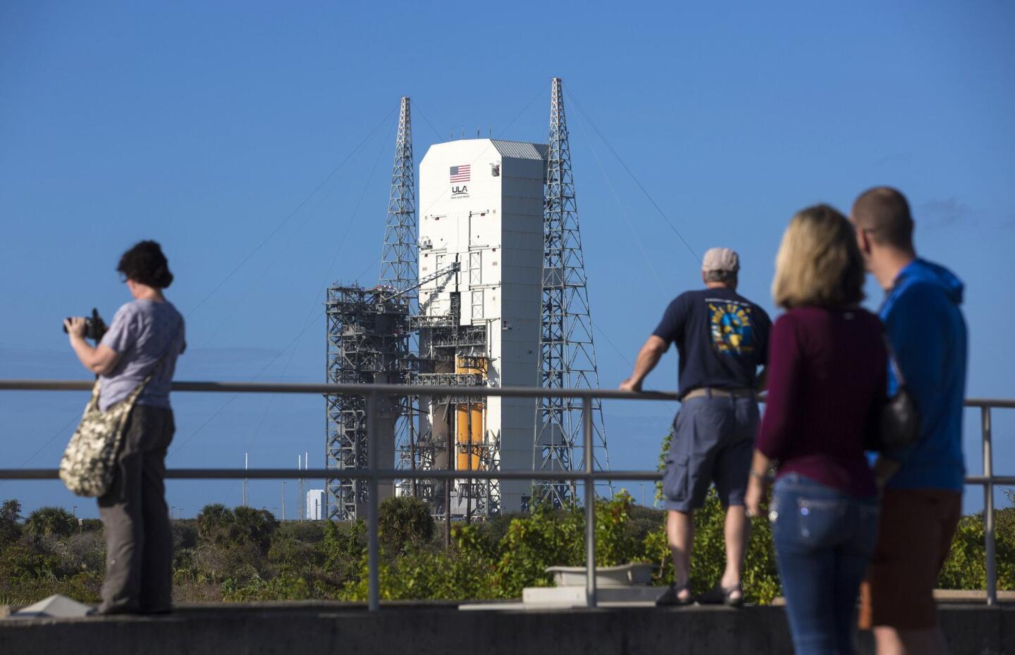 Tourists stand on the original Apollo 1 launch pad overlooking the Delta IV Heavy rocket with the Orion spacecraft on Space Launch Complex 37B pad at the Cape Canaveral Air Force Station in Cape Canaveral, Florida
