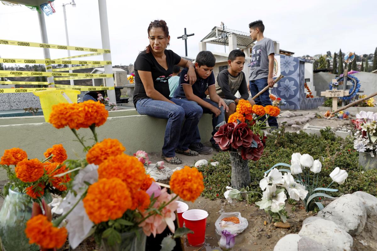 Esperanza Navarro, 35, with her nephews, visits the grave of her brother Cipriano, who was shot and killed in front of his home on Sept. 7, 2017. (Gary Coronado / Los Angeles Times)