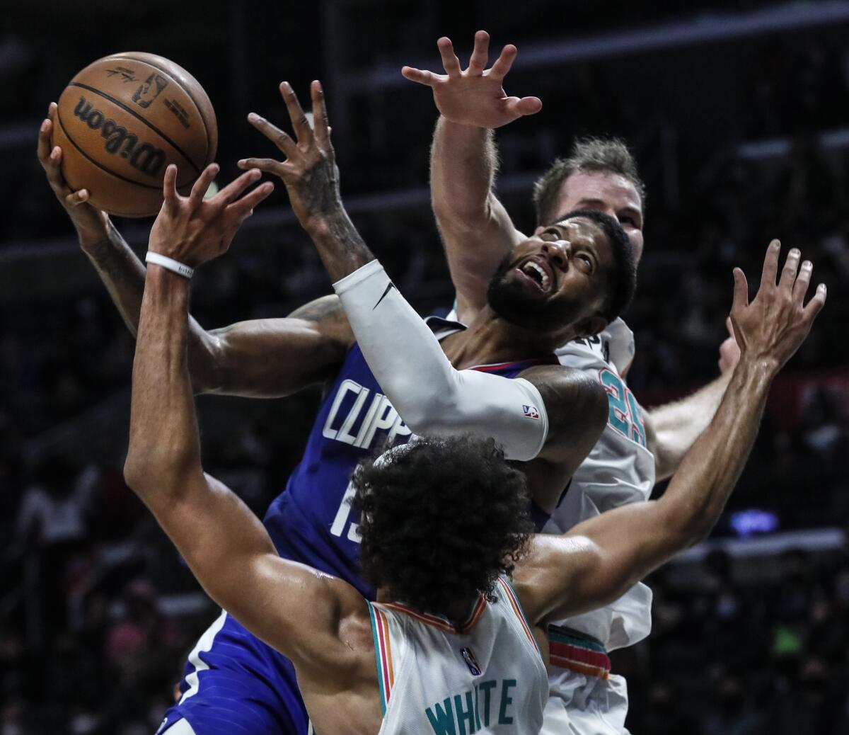 Clippers guard Paul George struggles to shoot over San Antonio Spurs guard Derrick White and center Jakob Poeltl.