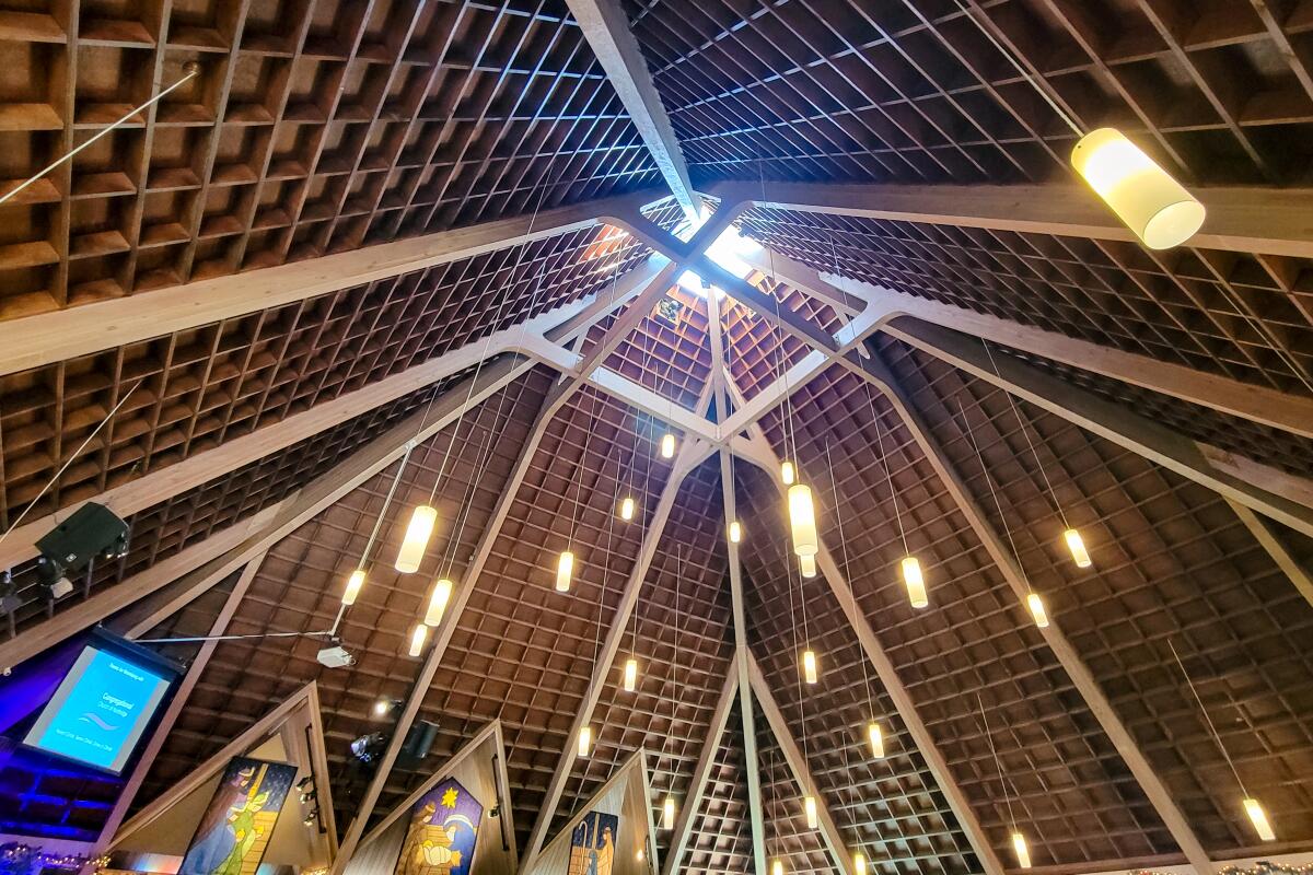 A richly textured pyramidal ceiling with a skylight at its peak and hanging cylindrical light fixtures.