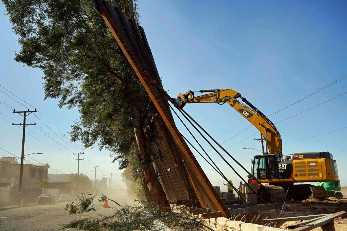 A construction crew works on a fallen section of the border wall as seen from Mexicali, Mexico, on Wednesday. Newly installed panels in Calexico, Calif., fell over in high winds, landing on trees on the Mexican side of the border.