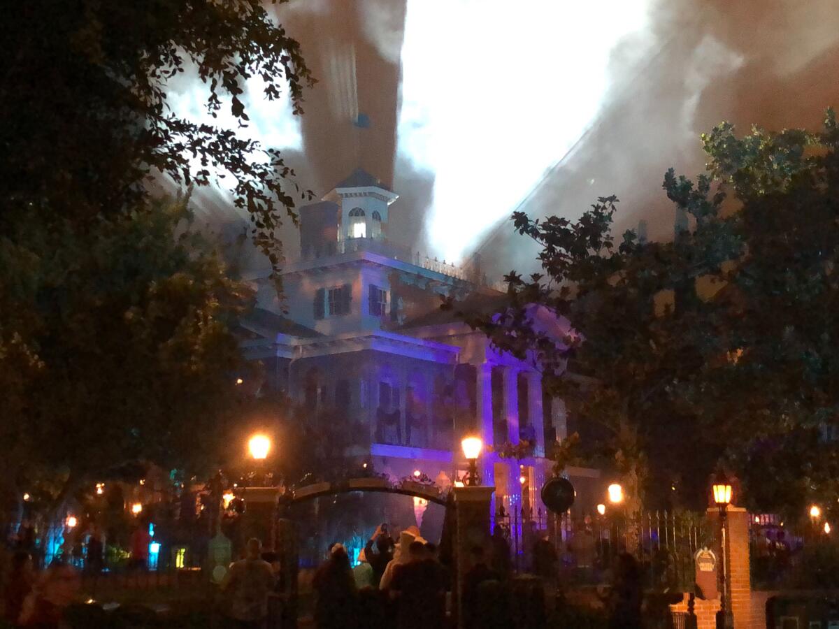 The exterior of a spooky house with mist and lantern light.