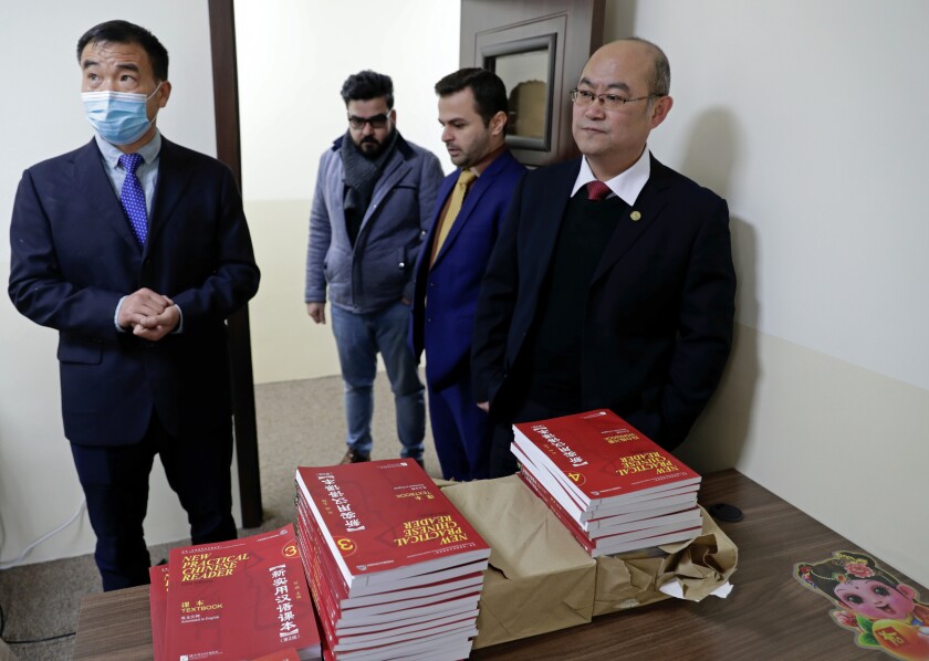Chinese lecturer, Zhiwei Hu, left, teachers and officials of the Chinese Language Department stand in front of Chinese language books intended for students in Salahaddin University in Irbil, Iraq, Wednesday, Jan. 19, 2021. The Chinese language school in northern Iraq is attracting students who hope to land jobs with a growing number of Chinese companies in the oil, infrastructure, construction, and telecommunications sectors in the region. (AP Photo/Khalid Mohammed)