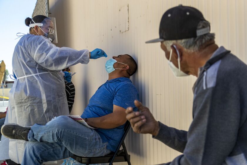 COACHELLA, CA - FEBRUARY 10, 2021: Medical assistant Trisha Edwards administers a Rapid COVID-19 test to farmworker Fernando Benitez of Thermal before getting the coronavirus vaccine at the Central Neighborhood Health Foundation on February 10, 2021 in Coachella, California. Fifty farmworkers are getting the vaccine here. Though farmworkers are among groups considered to be high priority for vaccines, rollout has been slow.(Gina Ferazzi / Los Angeles Times)