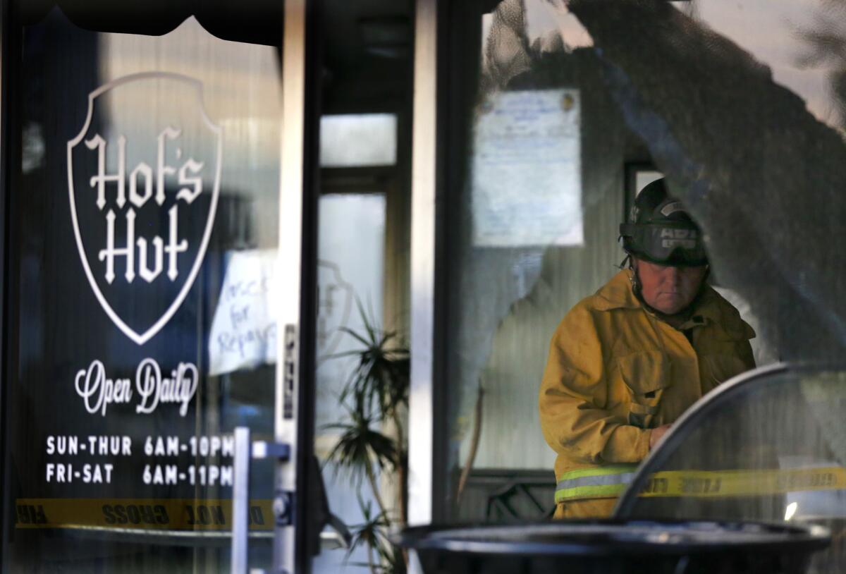 A Long Beach Fire Department investigator looks at the damage in Hof's Hut restaurant Monday after the second of two fires caused extensive damage to the landmark restaurant.