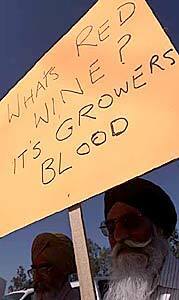 Raghbir Singh Khosa, left, and Jeon Gill, two grape growers from Caruthers, Calif., holding up signs in front of Gallo Winery.