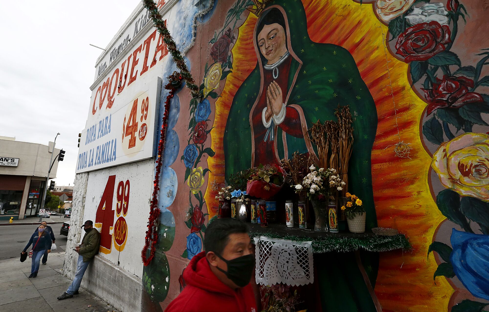 People walk past a mural of the Virgin of Guadalupe in the Westlake area of Los Angeles.