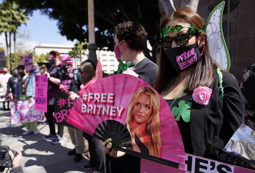 Protesters hold signs and a fan that says #FreeBritney.