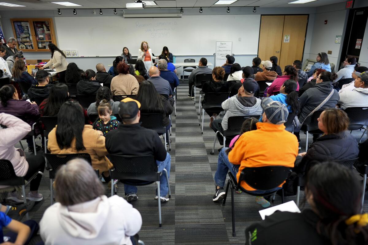 Audience members listen to a community organizer during an informational meeting for migrants in Des Moines.