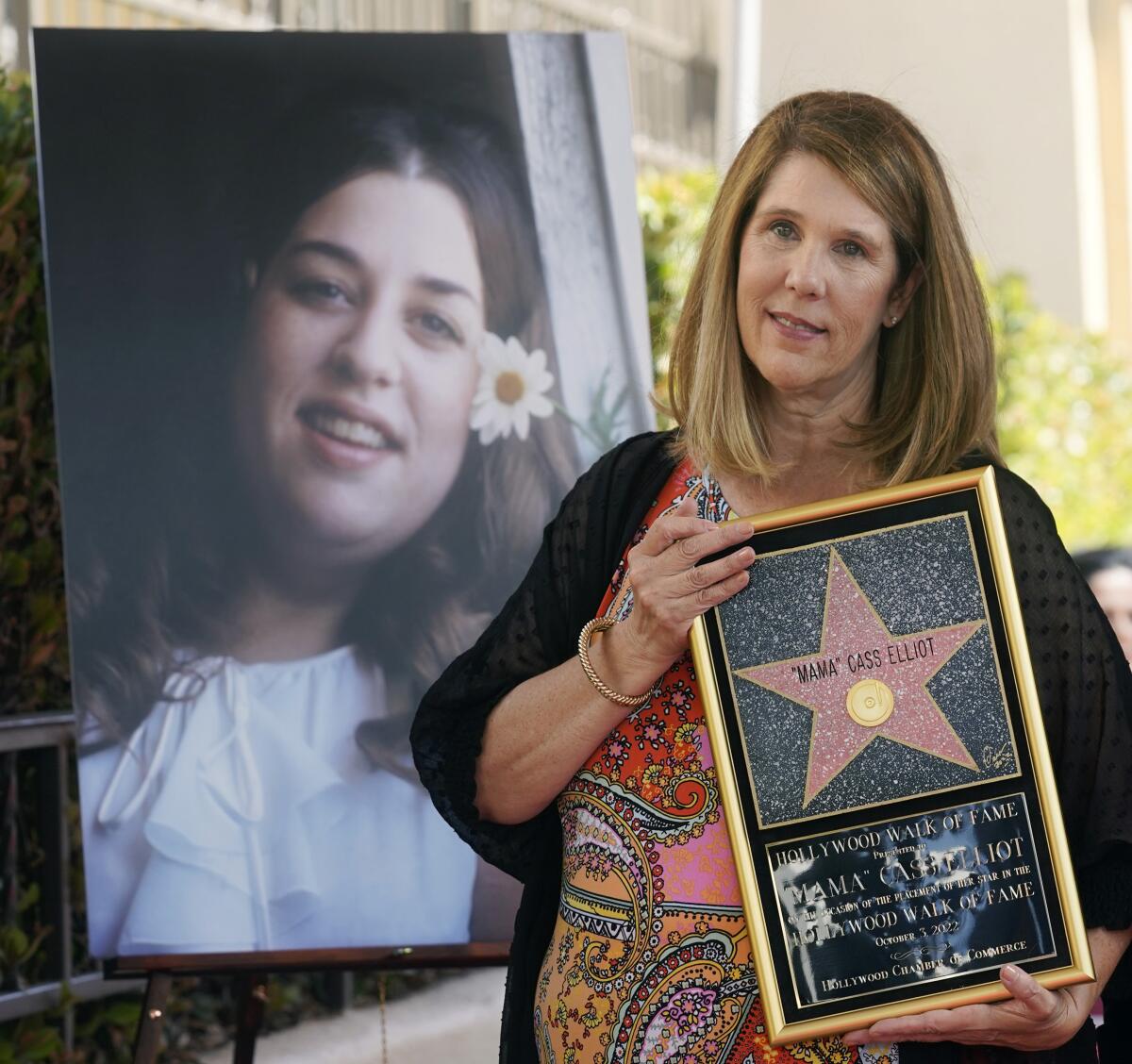 Owen Elliot-Kugell holds a framed Hollywood Walk of Fame star next to a photo of 'Mama' Cass Elliot