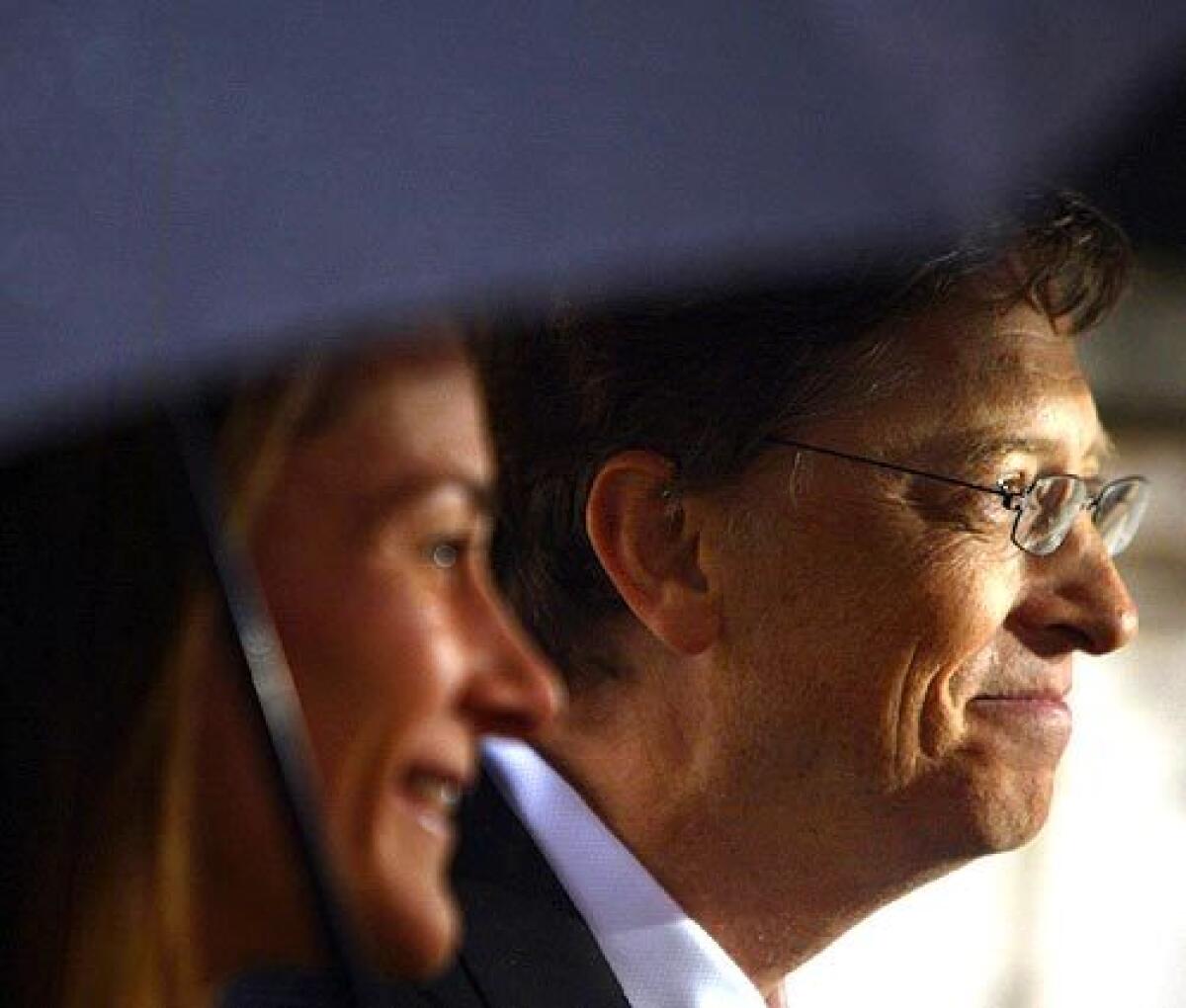 Chairman and Chief Software architect of Microsoft Bill Gates and his wife Melinda stand beneath an umbrella after he received an honorary knighthood at Buckingham Palace in London..