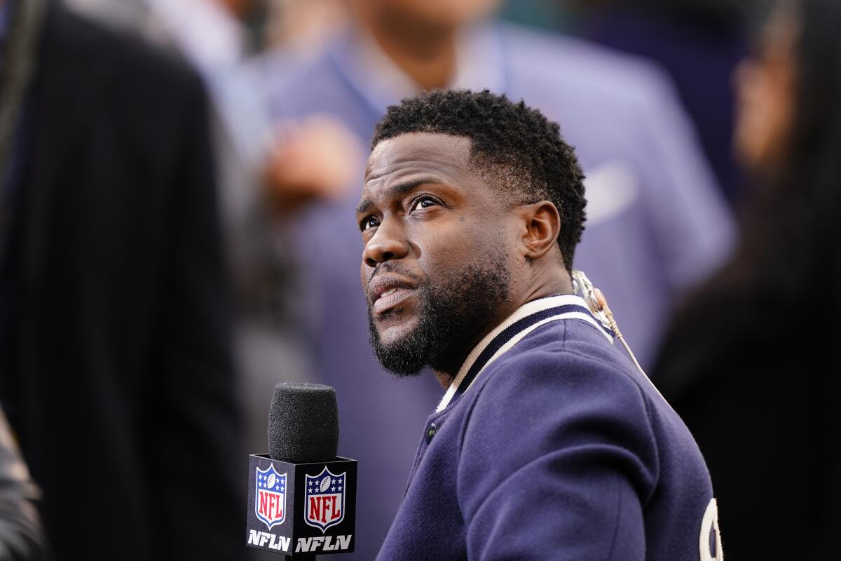 A man with a beard wearing a blue jacket and holding an NFL Network microphone