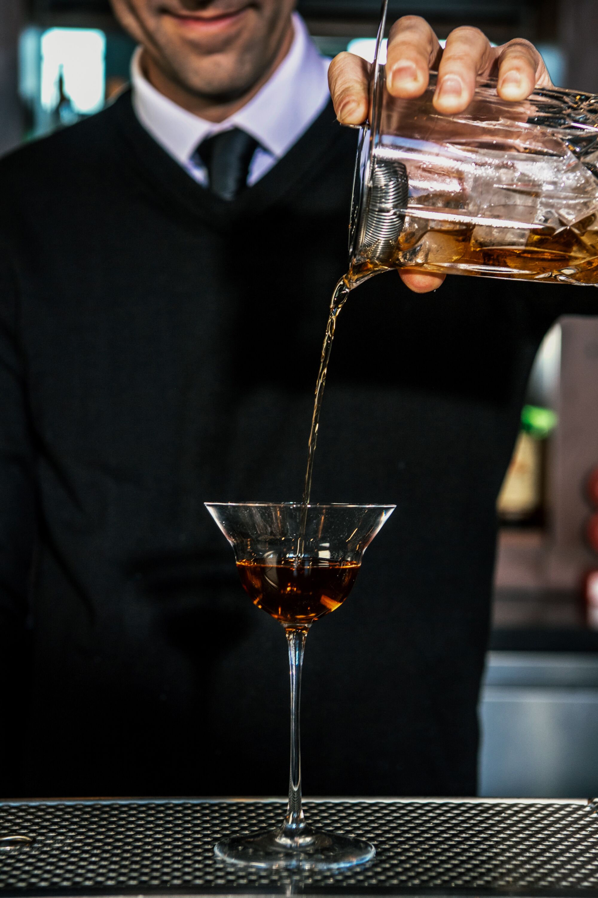 A bartender pours a cocktail.