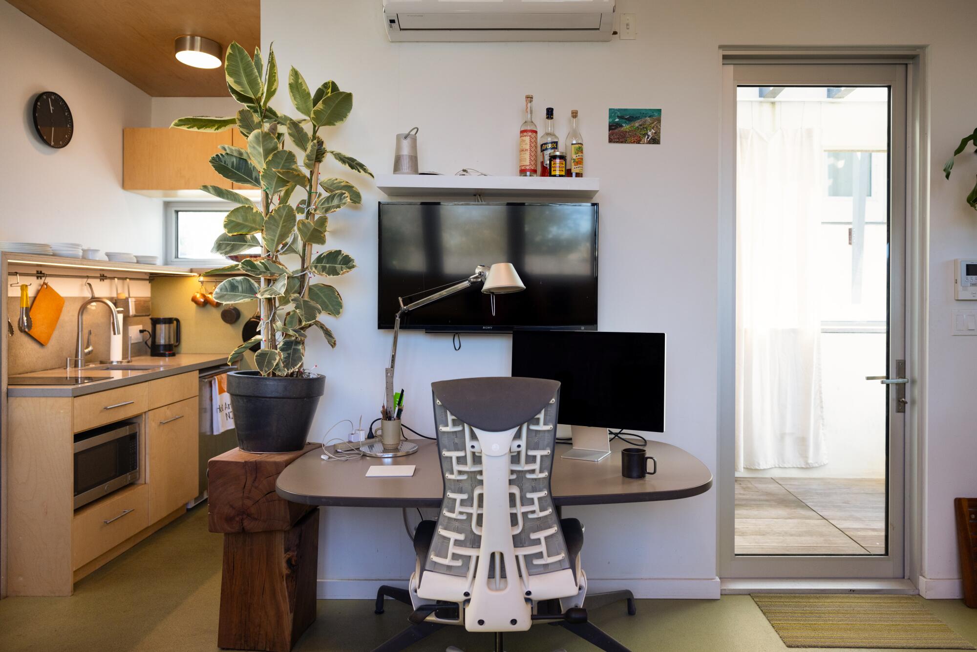 A compact home office wedged between a door and a galley kitchen in an ADU.