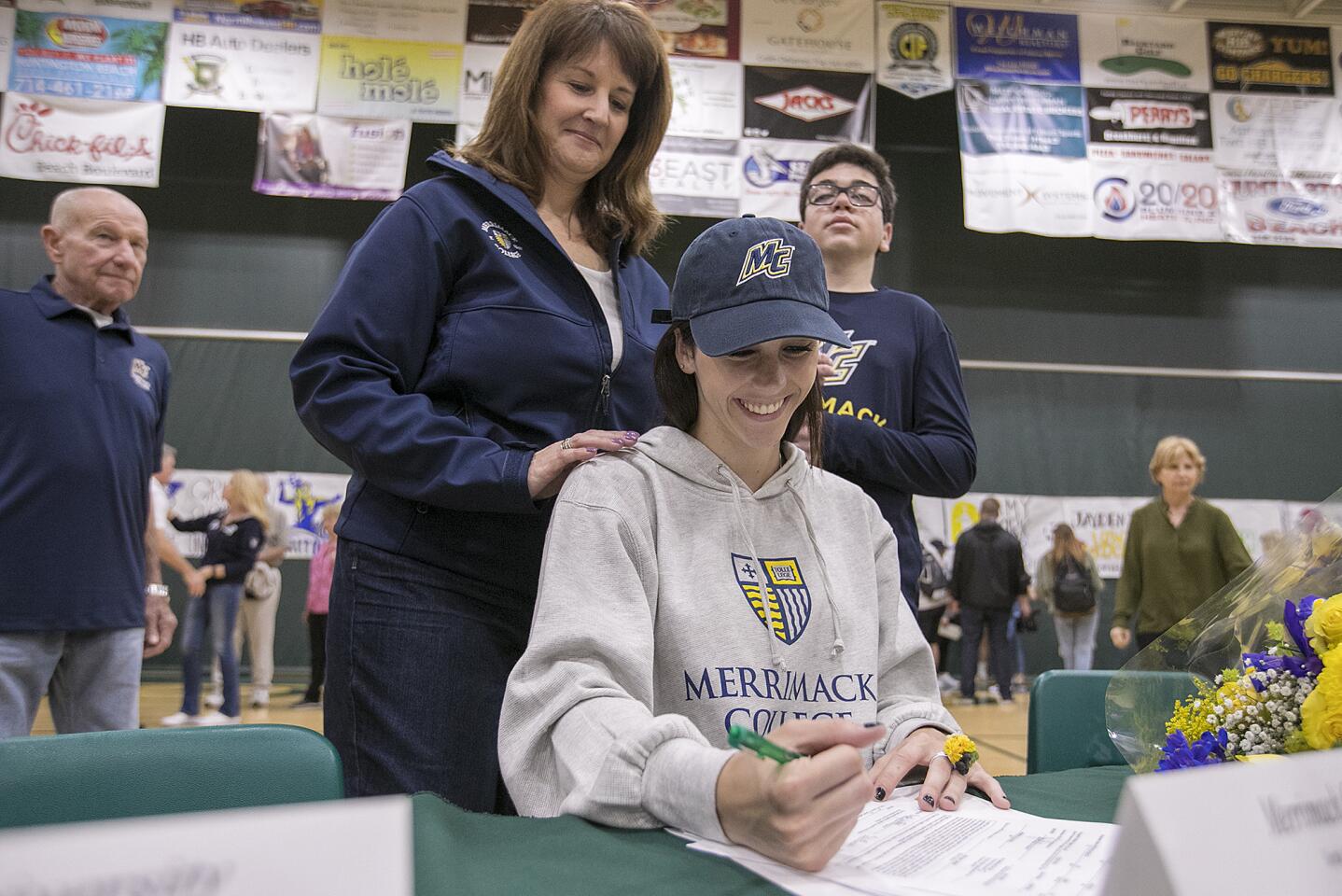 Michele Leestma and her son Sawyer, right, watch as her daughter Brooke signs her acceptance to Merrimack College during National Signing Day at Edison High School on Wednesday, April 11.