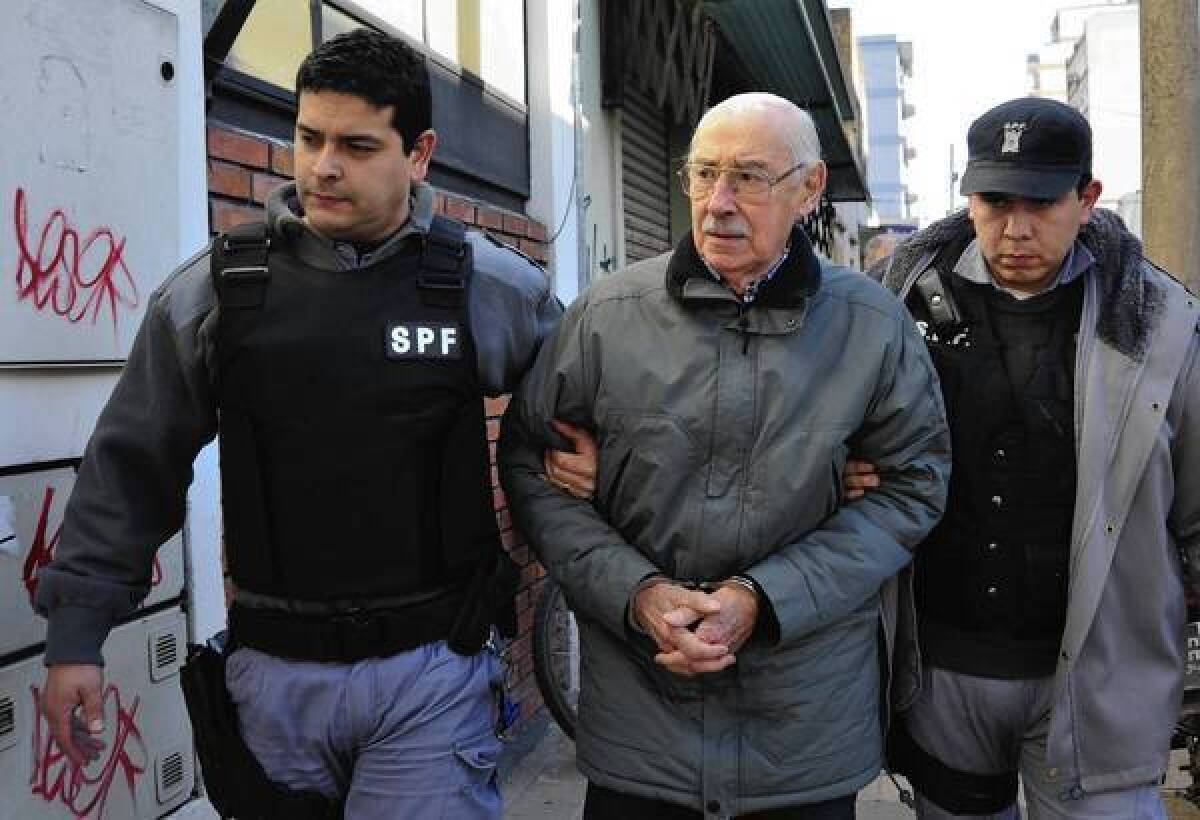 Jorge Rafael Videla is escorted into a courtroom in Buenos Aires last year. He died of natural causes in Marcos Paz prison on Friday.
