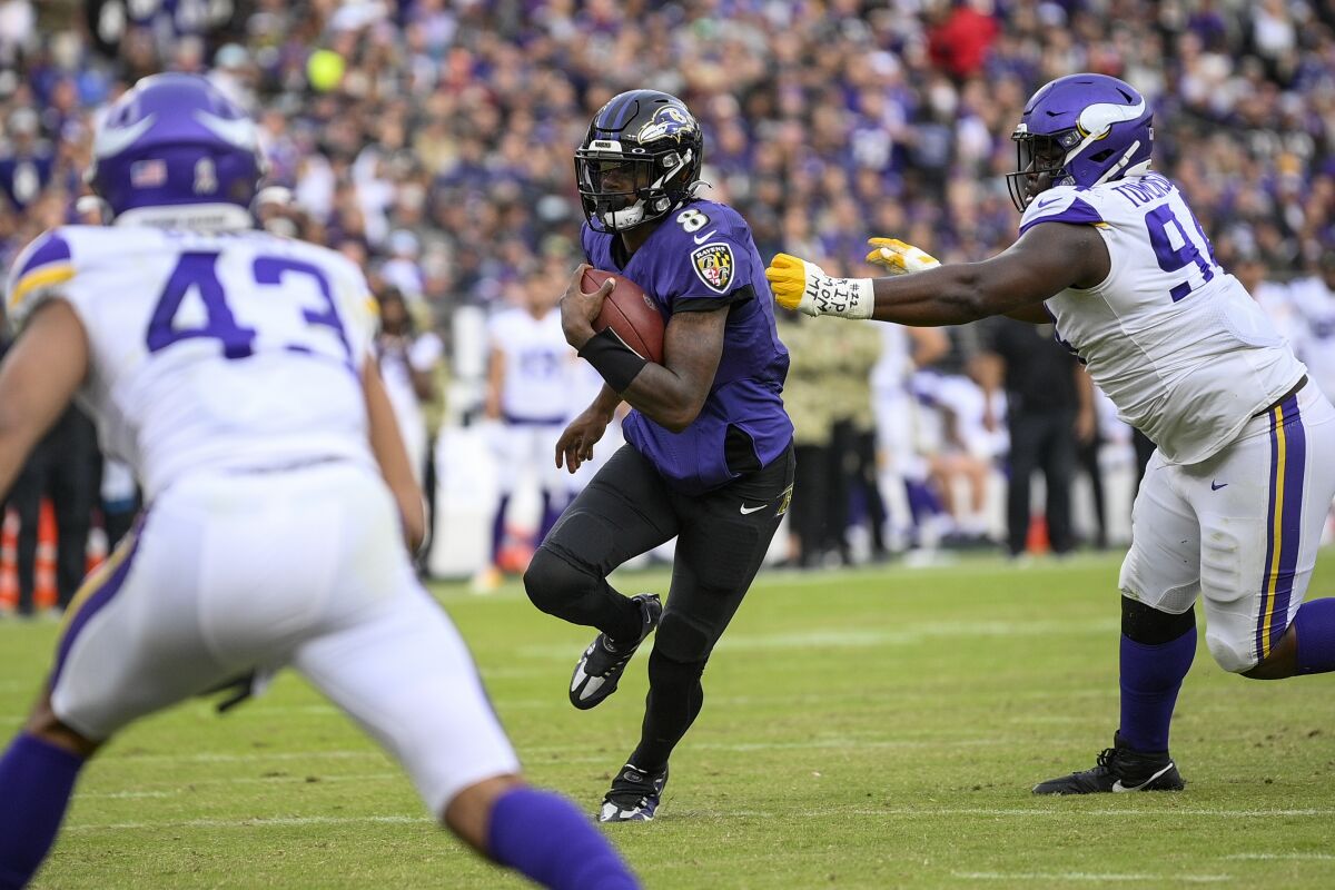 Baltimore Ravens quarterback Lamar Jackson (8) gets away from Minnesota Vikings defensive tackle Dalvin Tomlinson (94) during the second half of an NFL football game, Sunday, Nov. 7, 2021, in Baltimore. (AP Photo/Nick Wass)