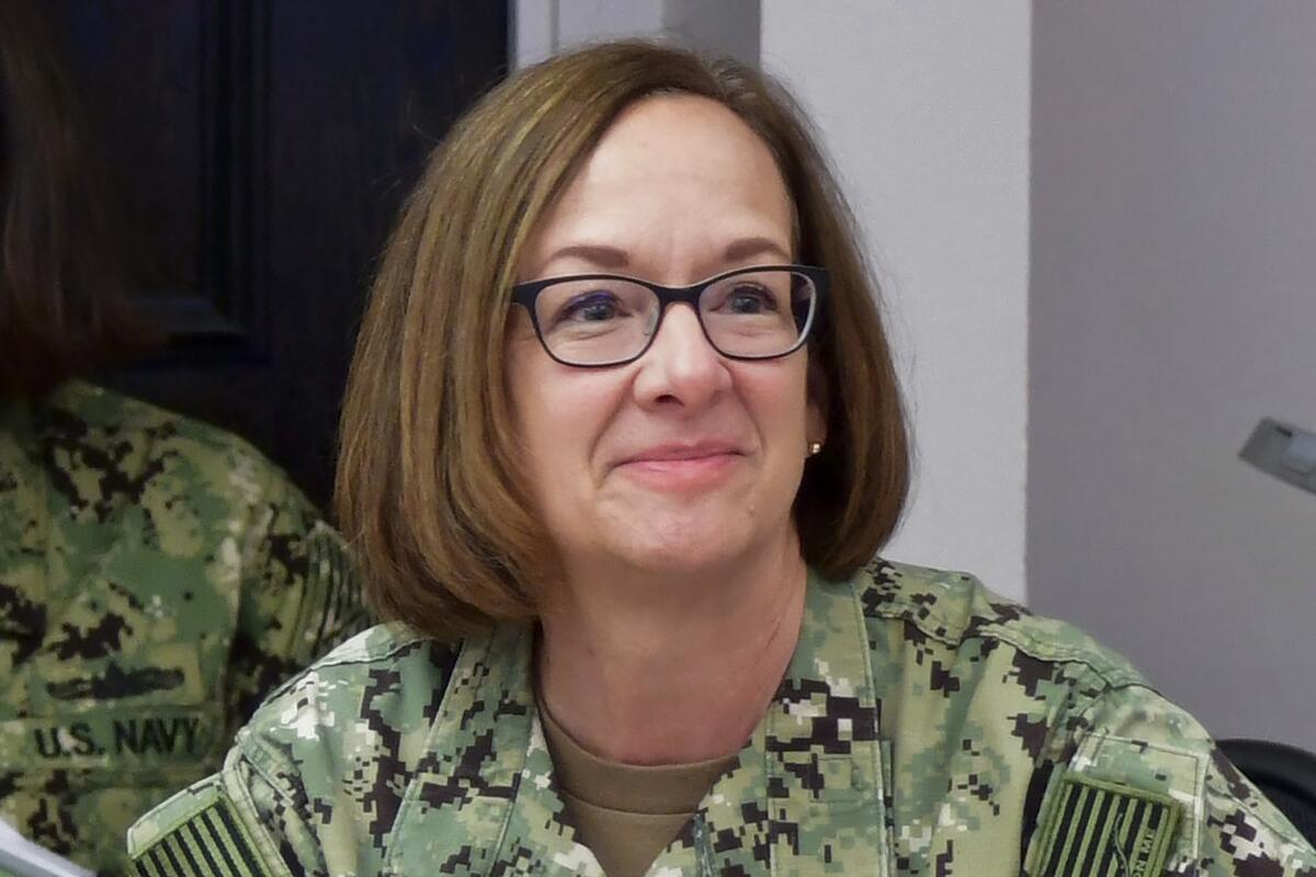 A woman in camouflage attire smiles.