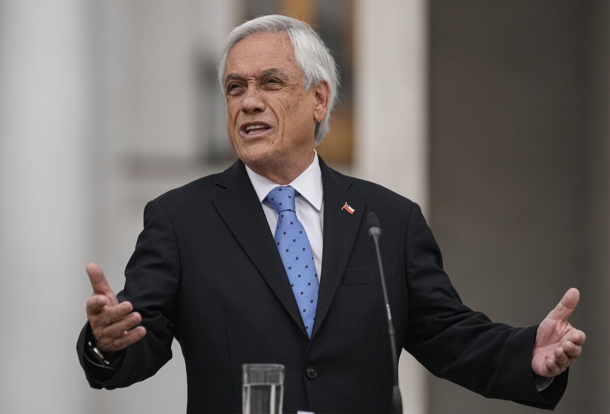 Chilean President Sebastian Piñera gestures while standing at a microphone. 