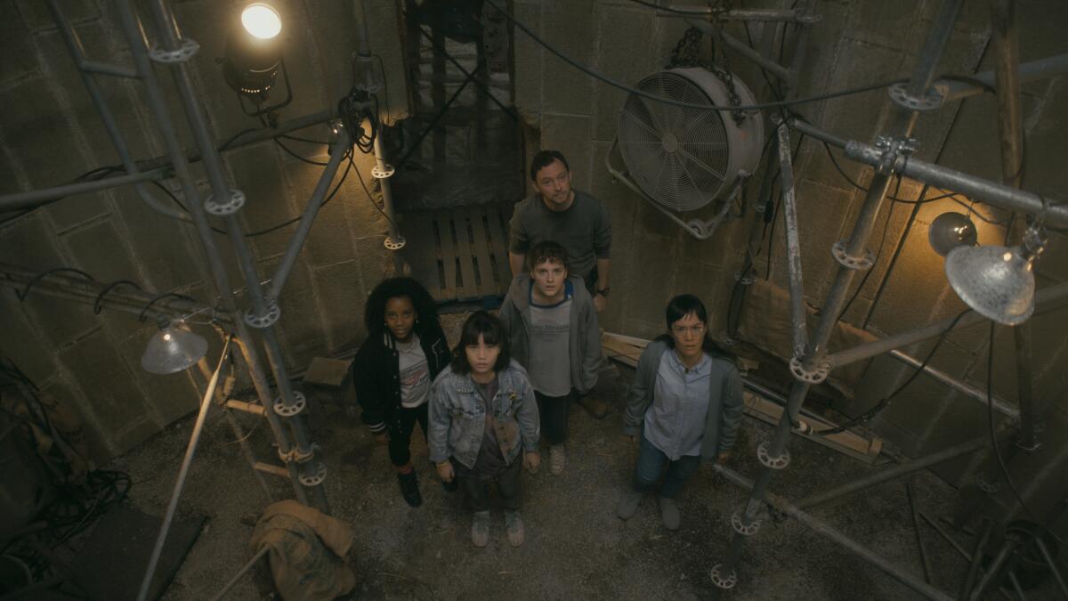 a man, a woman, and three girls looking upward inside a barn