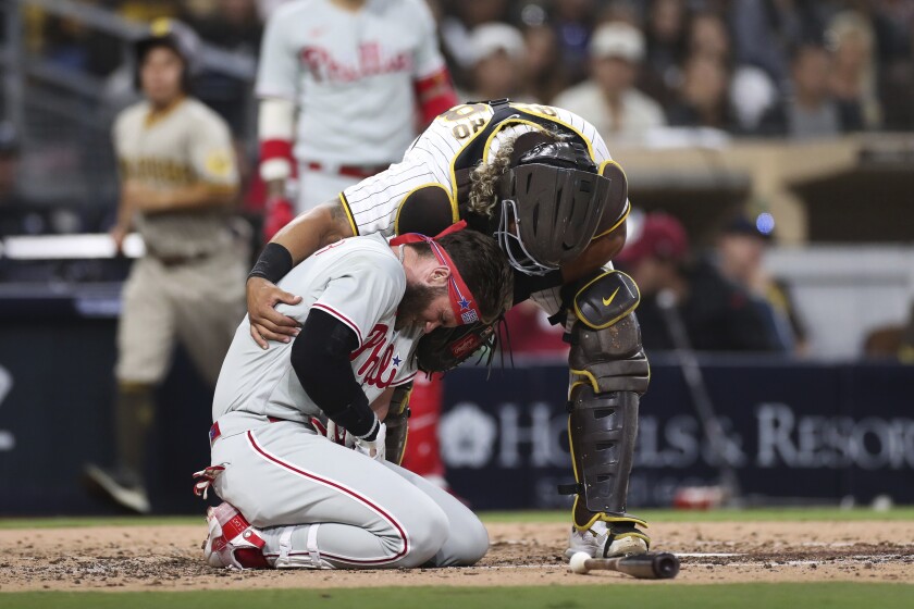 Philadelphia Phillies' Bryce Harper, bottom, reacts after being hit by a pitch from San Diego Padres' Blake Snell as Padres catcher Jorge Alfaro checks on him duirng the fourth inning of a baseball game Saturday, June 25, 2022, in San Diego. (AP Photo/Derrick Tuskan)