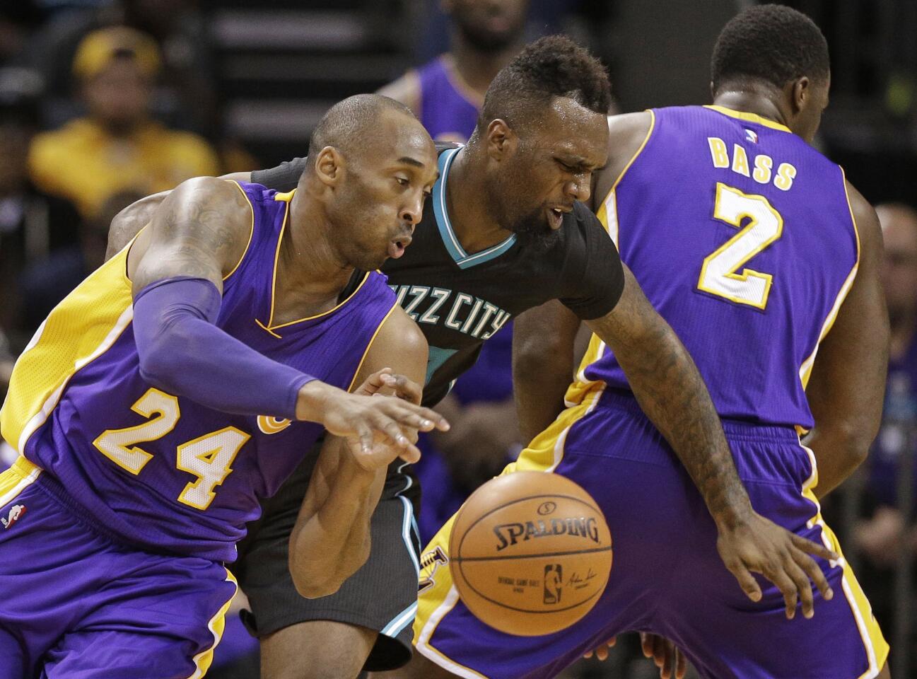 Lakers forward Kobe Bryant (24) drives past Hornets forward P.J. Hairston, center, as Brandon Bass tries to set a screen in the first half.