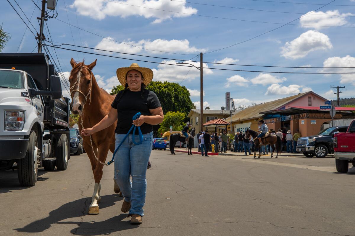 A woman leads a horse down a city street.