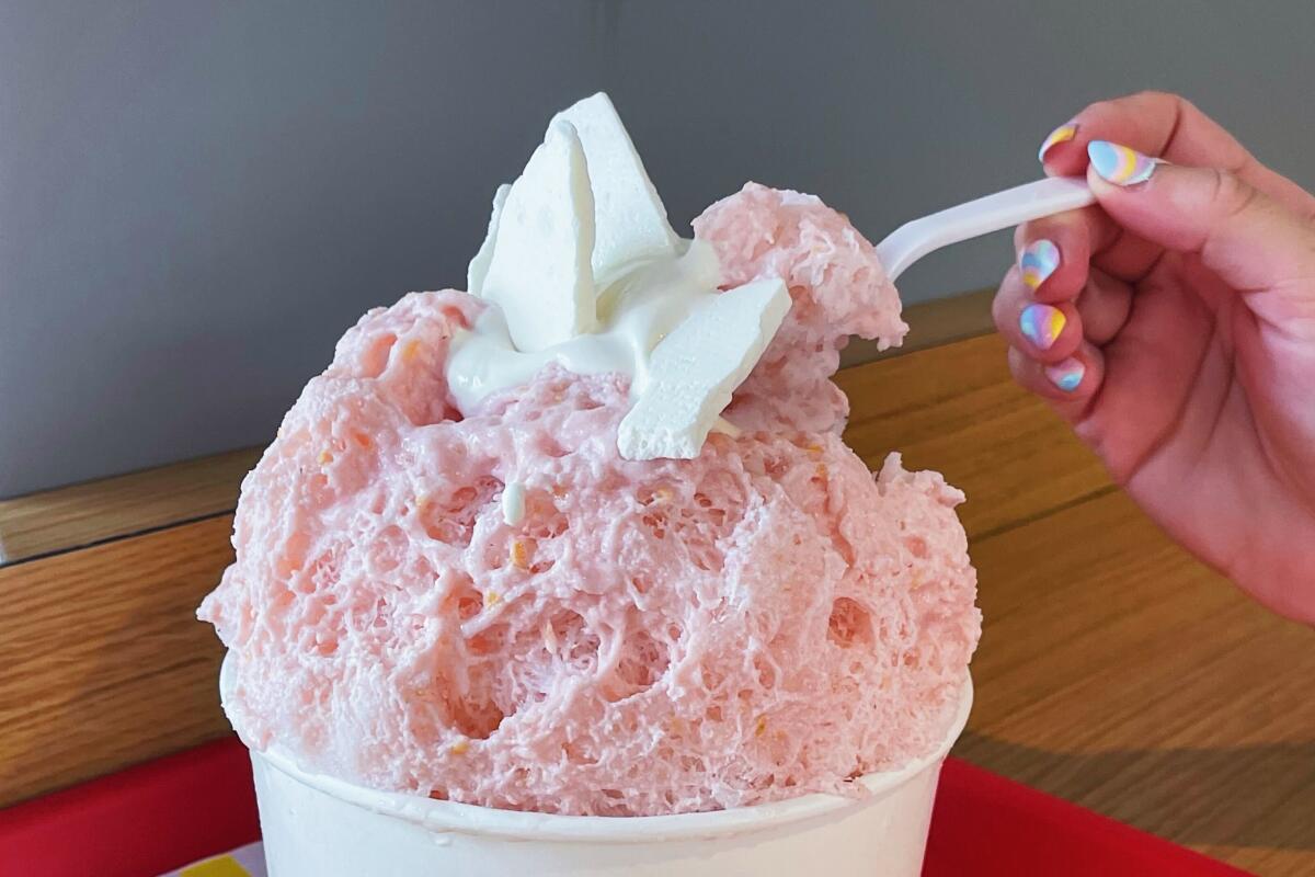 A hand scoops a spoonful of pink, meringue-topped shaved ice from Katsu Sando.