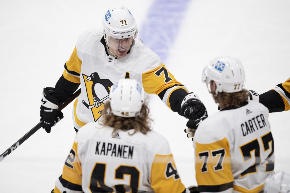 Pittsburgh Penguins center Evgeni Malkin (71) congratulates center Jeff Carter (77) for his empty-net goal against the Anaheim Ducks in the third period of an NHL hockey game in Anaheim, Calif., Tuesday, Jan. 11, 2022. (AP Photo/Kyusung Gong)