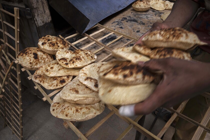 FILE - A worker collects Egyptian traditional 'baladi' flatbread, at a bakery, in el-Sharabia, Shubra district, Cairo, Egypt, Wednesday, March 2, 2022. Egypt will receive a $500 million loan from the World Bank to help finance its wheat purchases as prices skyrocket because of the Russian invasion of Ukraine, the Bank said Wednesday. The funds, approved Tuesday by the World Bank Board of Executive Directors, aim at supporting Egypt’s efforts to provide subsidized bread to poor and vulnerable households, it said. (AP Photo/Nariman El-Mofty, File)