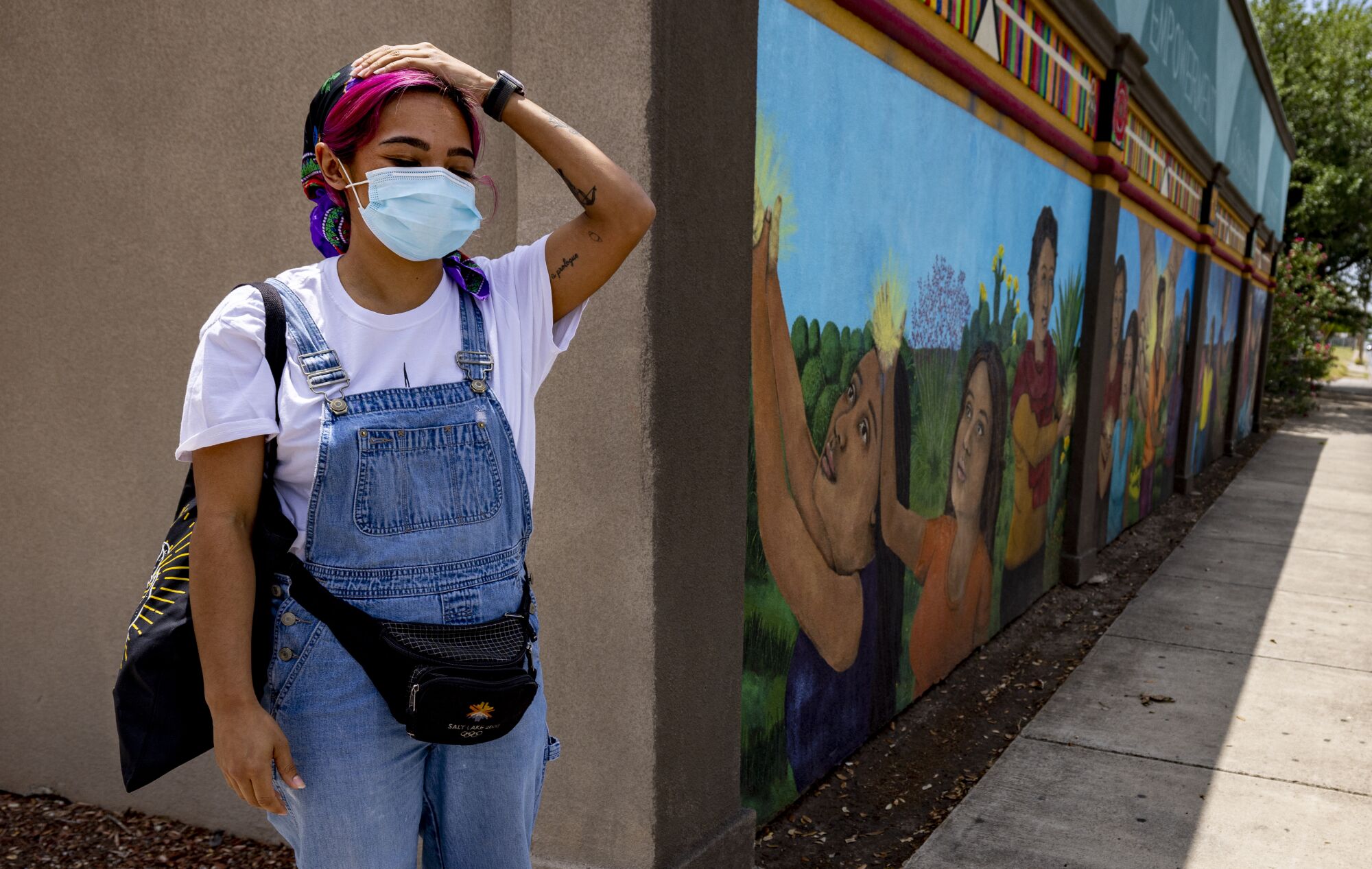 A woman wearing a mask stands on the street corner outside a clinic.