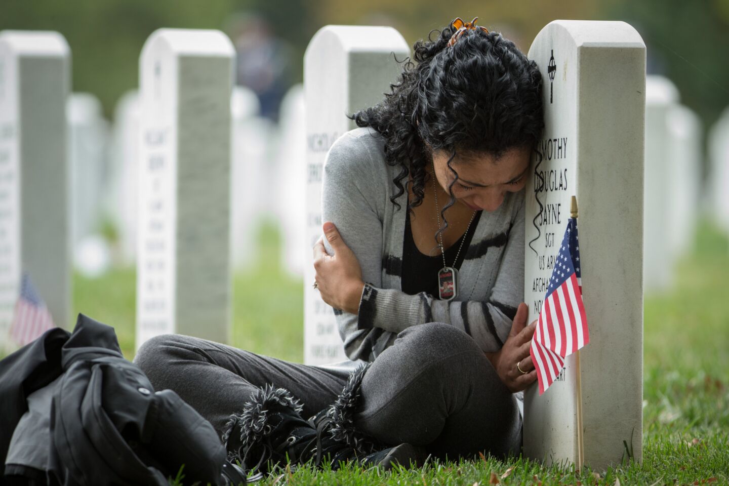 Thania Sayne of Effingham, Ill., leans on the headstone at the grave of her husband, Army Sgt. Timothy D. Sayne, during the playing of taps at a nearby burial service at Arlington National Cemetery.