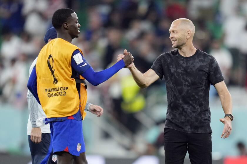 U.S. player Tim Weah and coach Gregg Berhalter celebrate after defeating Iran