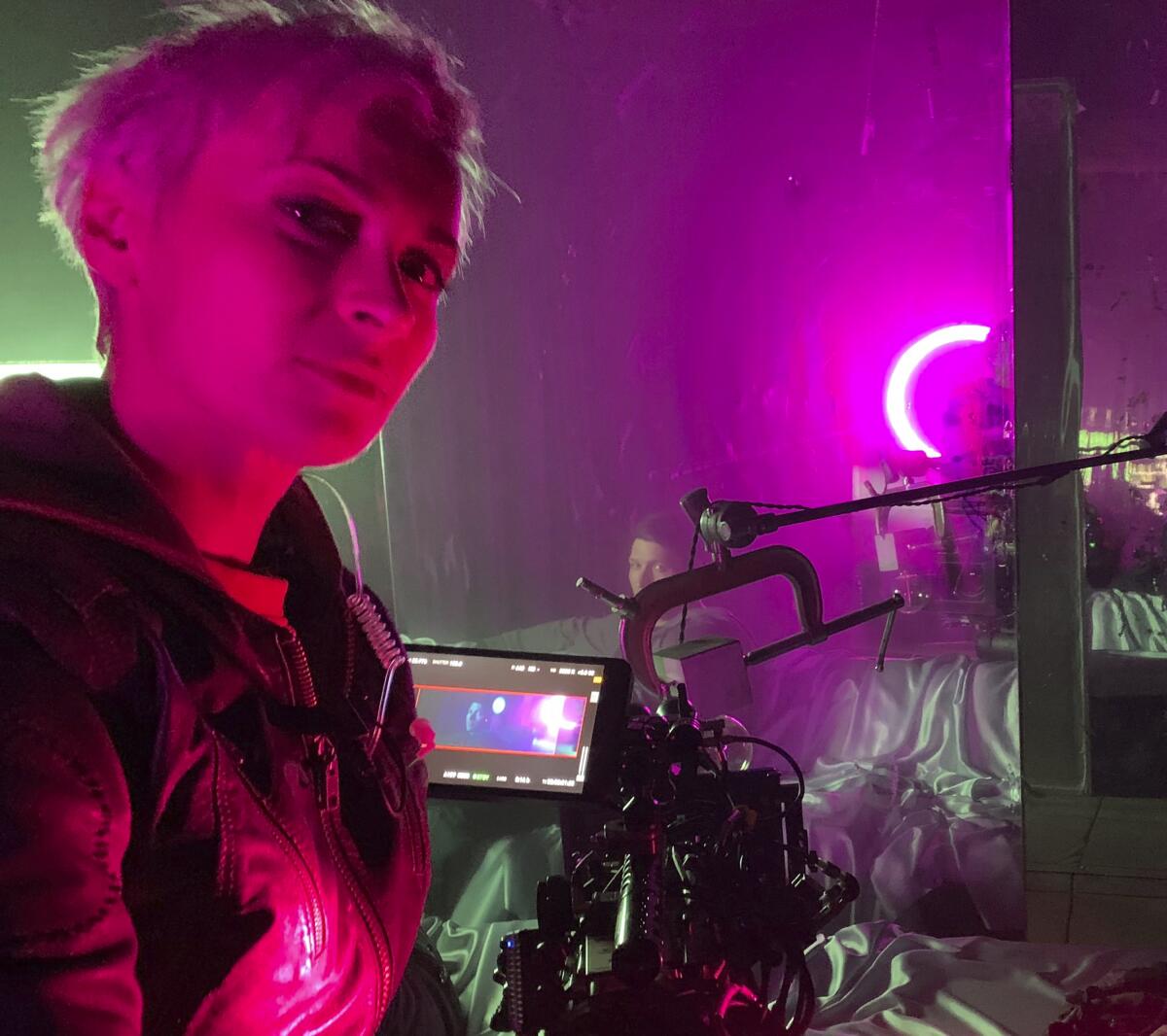 Cinematographer Halyna Hutchins is lit by red and purple lights on set