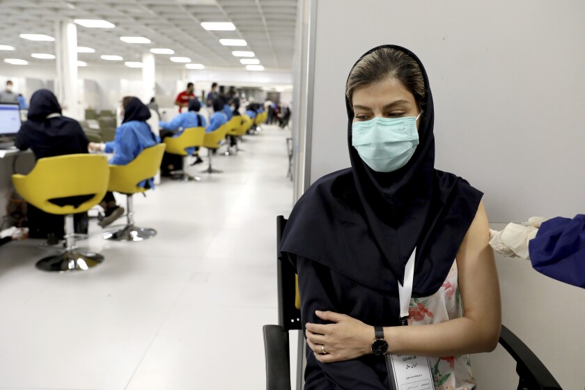 FILE - In this May 17, 2021 file photo, a medical worker receives the Sinopharm coronavirus vaccine at the Iran Mall shopping center in Tehran, Iran. Iran announced on Sunday, July 4, 2021, that it was reimposing coronavirus restrictions on major cities as the spread of the highly contagious delta variant spurs fears of another devastating surge in the nation. (AP Photo/Ebrahim Noroozi, File)