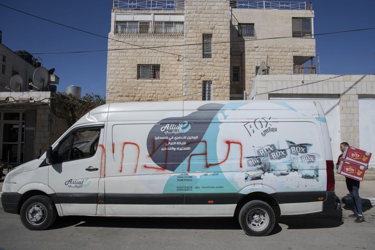 A Palestinian man unloads his vandalized vehicle painted with Hebrew that reads "price tag," after Israeli settlers vandalized residents properties overnight, in the West Bank city of Ramallah, Tuesday, Nov. 9, 2021. It was the latest in a series of so-called “price tag” attacks, in which hard-line Israeli nationalists attack Palestinians and vandalize their property in response to Palestinian militant attacks or perceived efforts by Israeli authorities to limit settlement activity. (AP Photo/Nasser Nasser)