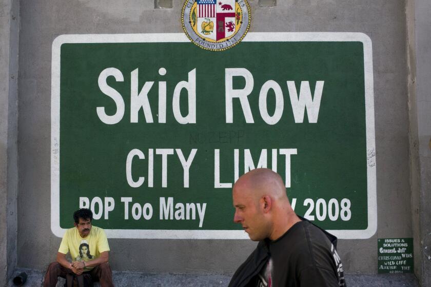 A man walks past a sign painted on a building in the Skid Row area of downtown Los Angeles on Nov. 17.