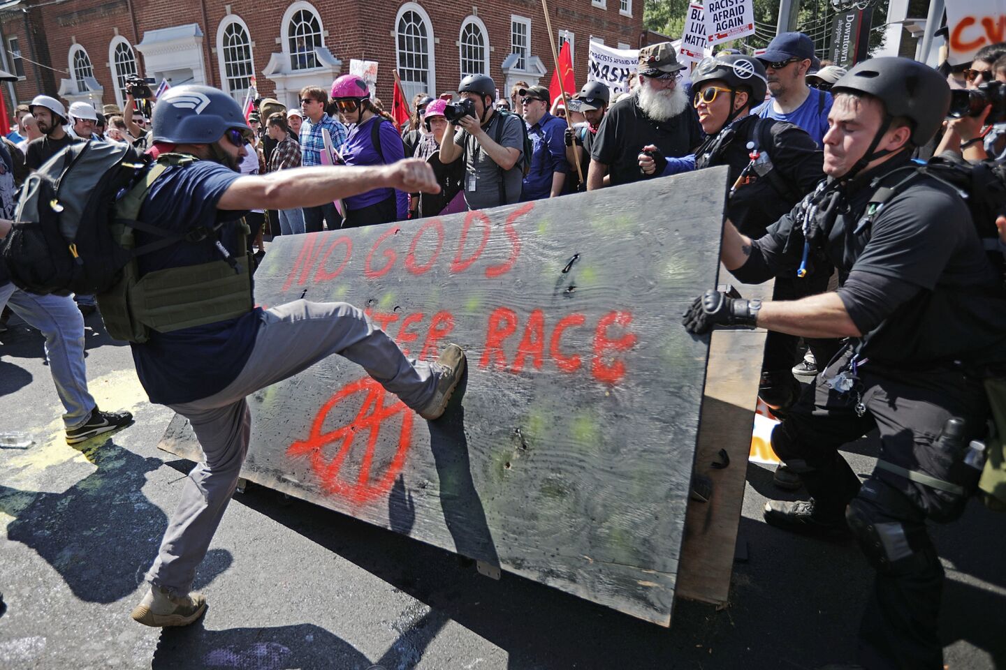 A man kicks a protest sign during the "Unite the Right" rally in Charlottesville, Va.