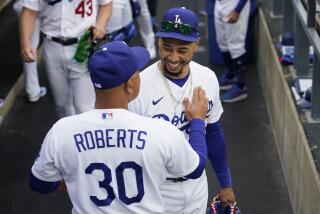 Los Angeles Dodgers manager Dave Roberts (30) greets right fielder Mookie Betts (50) in the dugout.