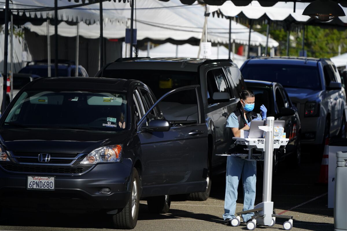 People wait in cars for a vaccination against the coronavirus at a new "vaccination superstation," Monday, Jan. 11, 2021, in San Diego. The site, which opened Monday, began providing large-scale COVID-19 vaccinations to health care workers. The U.S. is entering the second month of the biggest vaccination effort in history with a major expansion of the campaign, opening football stadiums, major league ballparks, fairgrounds, and convention centers to inoculate a larger and more diverse pool of people. (AP Photo/Gregory Bull)