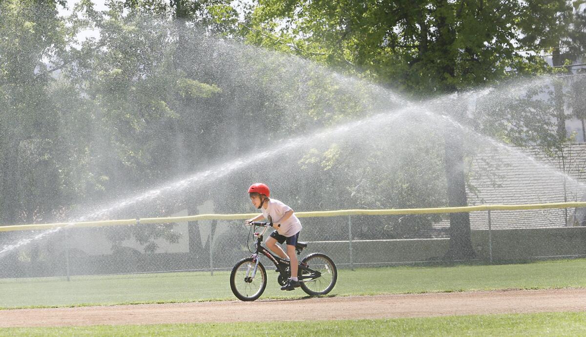 James Schulz rides through sprinklers at Brand Park on Friday, April 11, 2008.