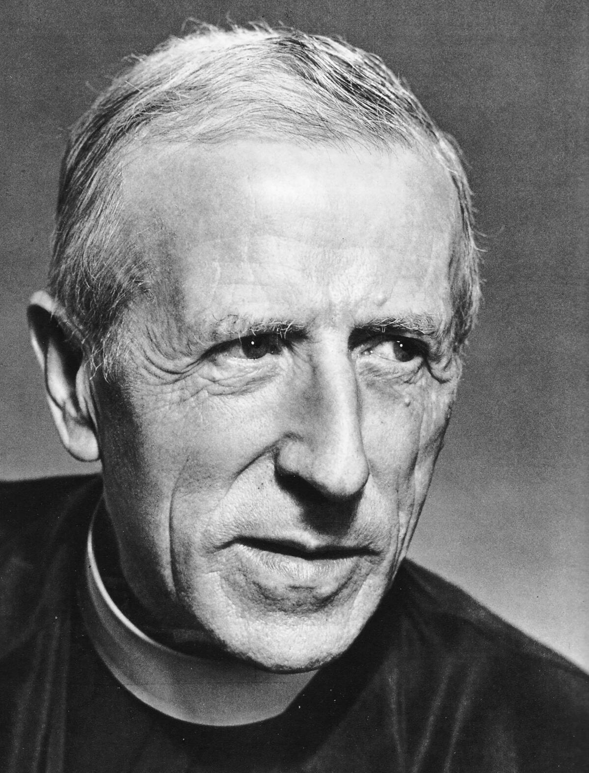 Father Pierre Tielhard de Chardin, a stern-looking priest in a black and white photo.
