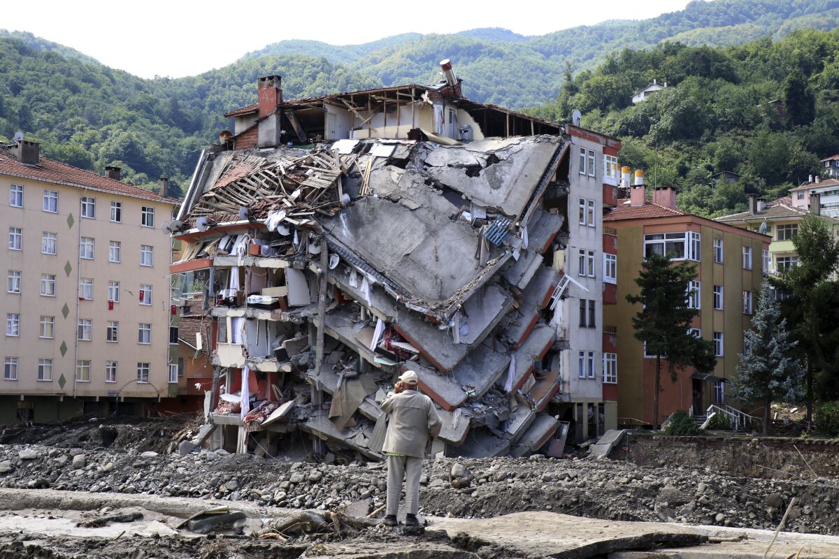 A man looks at destroyed building, in Bozkurt town of Kastamonu province, Turkey, Saturday, Aug. 14, 2021. The death toll from severe floods and mudslides in coastal Turkey has climbed to at least 44, the country's emergency and disaster agency said Saturday. Torrential rains that pounded the Black Sea provinces of Bartin, Kastamonu and Sinop on Wednesday caused flooding that demolished homes, severed at least five bridges, swept away cars and rendered numerous roads unpassable. (AP Photo)